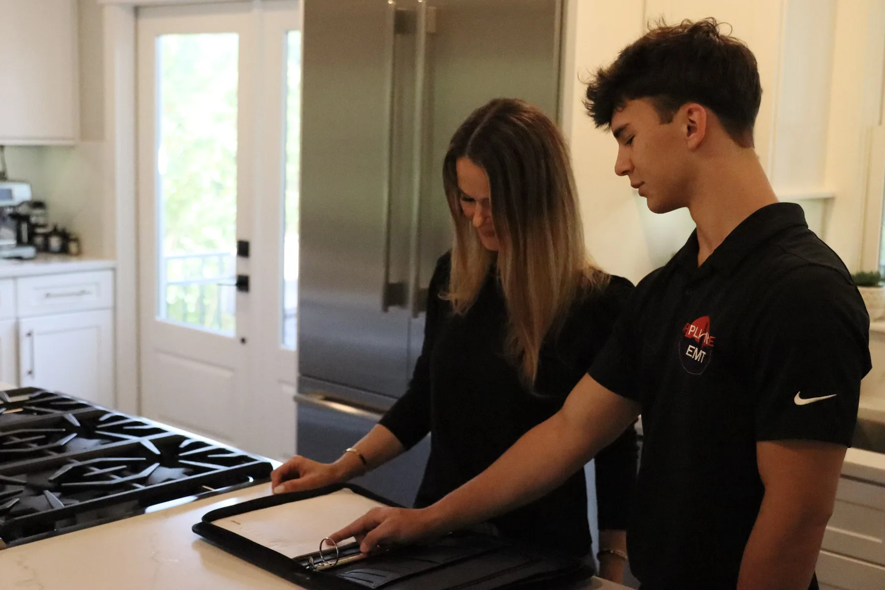 Appliance EMT technician going through a kitchen appliance repair with a customer