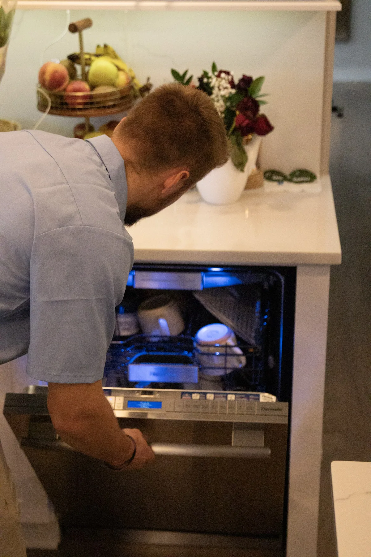 Appliance EMT technician servicing a built-in dishwasher in a customer kitchen