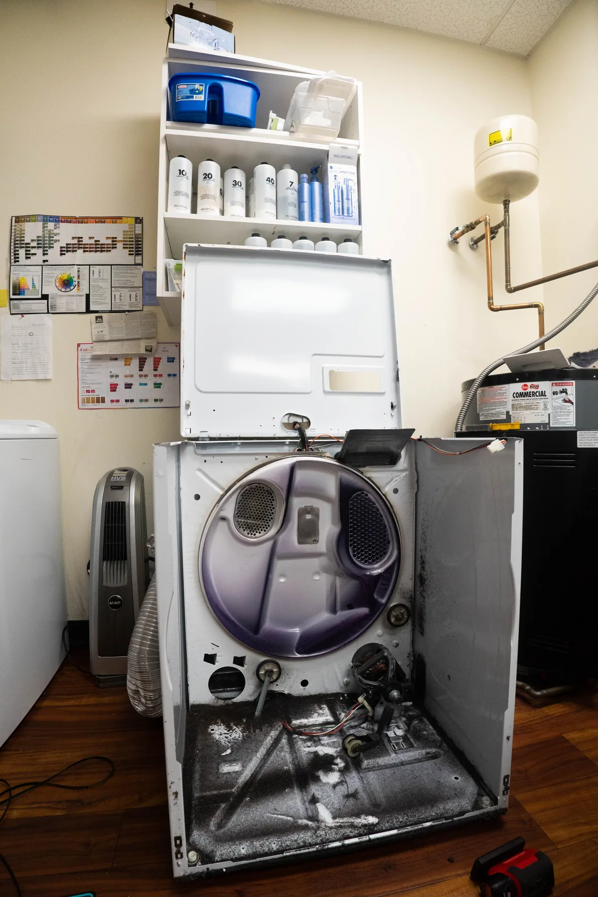 A dryer opened up for repair in a laundry room