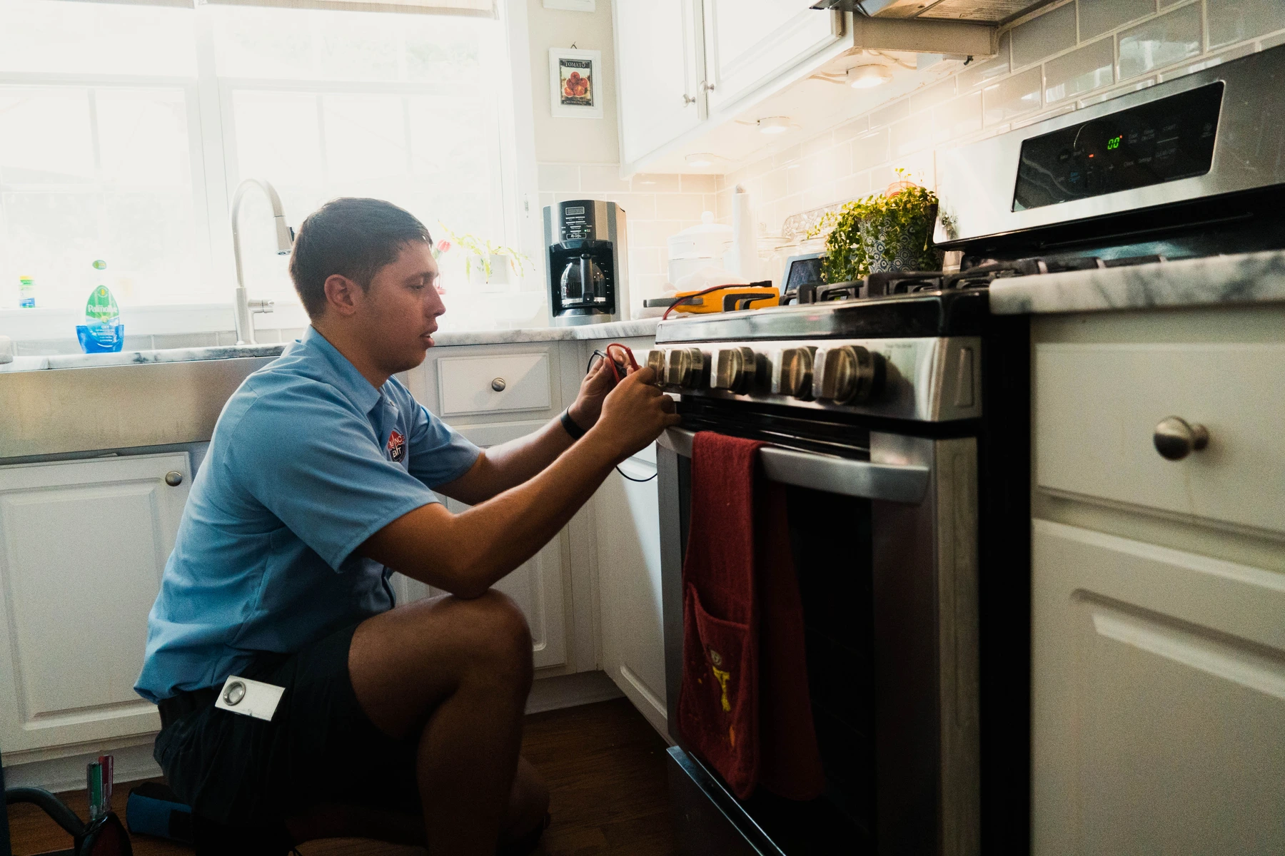 Appliance EMT technician adjusting the control knobs on a gas range