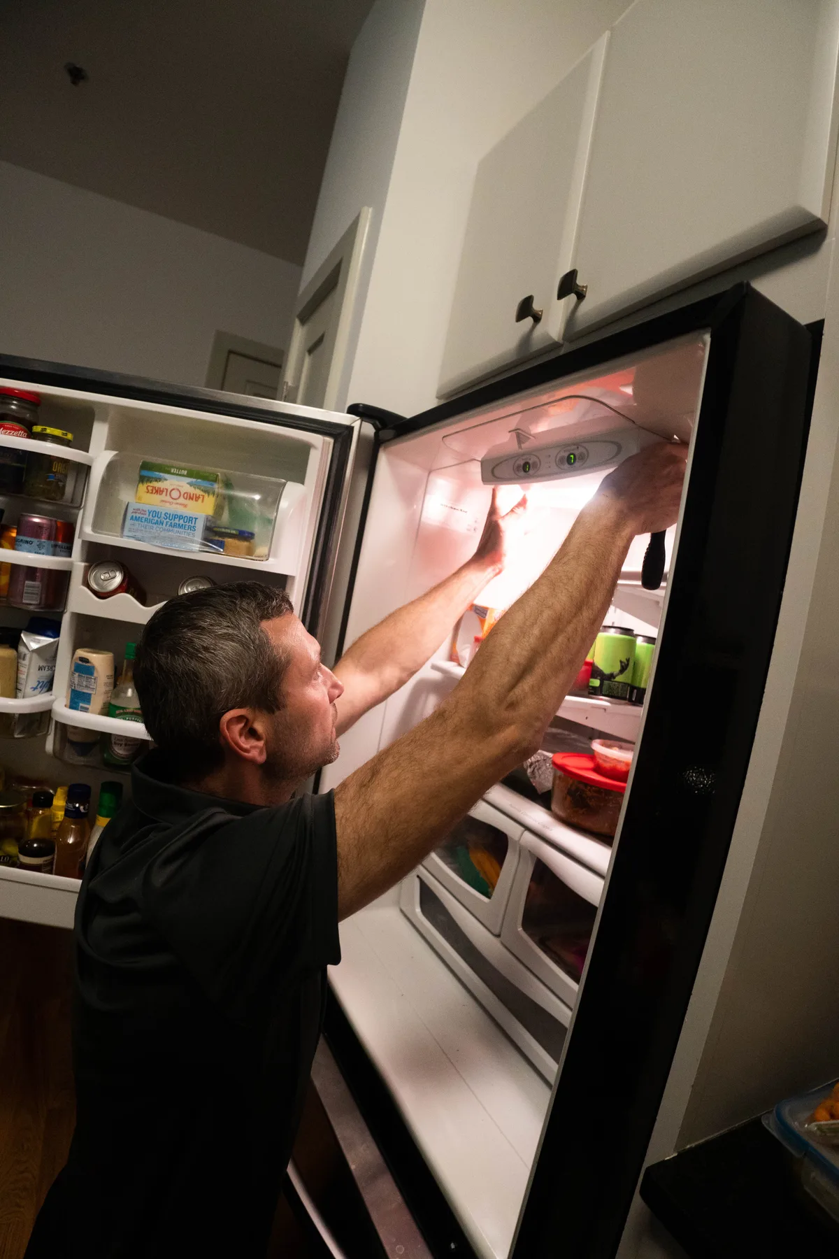 Appliance EMT technician checking the controls inside a refrigerator during a service call